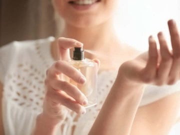 How and Where To Apply Perfume Properly Beautiful young woman with bottle of perfume at home, closeup