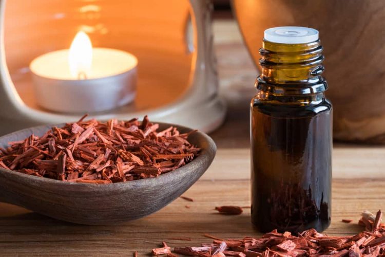 Smooth Santalum: 11 Of The Best Sandalwood Colognes A bottle of sandalwood essential oil with sandalwood pieces